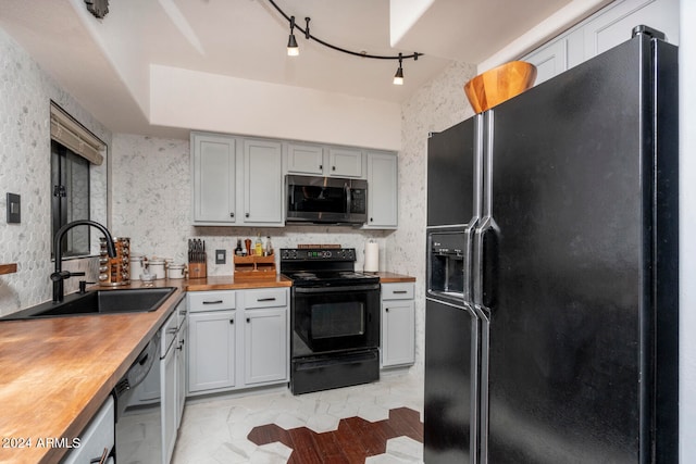 kitchen with sink, wooden counters, rail lighting, black appliances, and gray cabinets