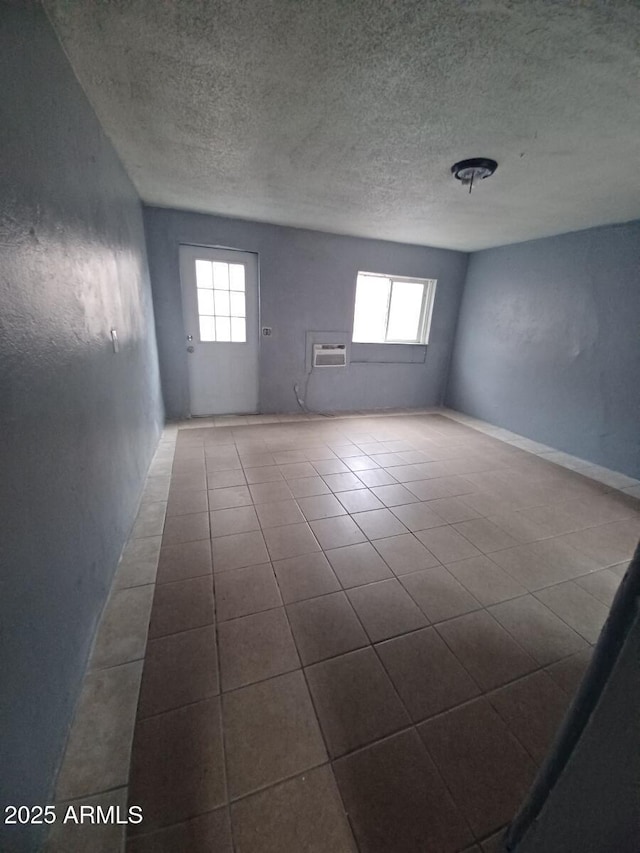 unfurnished room with tile patterned floors, a textured ceiling, and a wall unit AC