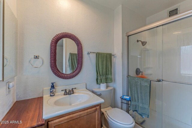 full bathroom featuring vanity, wood finished floors, visible vents, a shower stall, and toilet