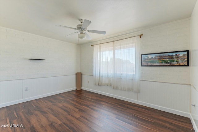 spare room featuring baseboards, dark wood-style floors, and a ceiling fan