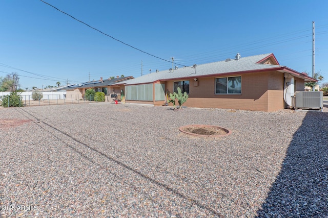 view of front of home with brick siding, central AC, and fence