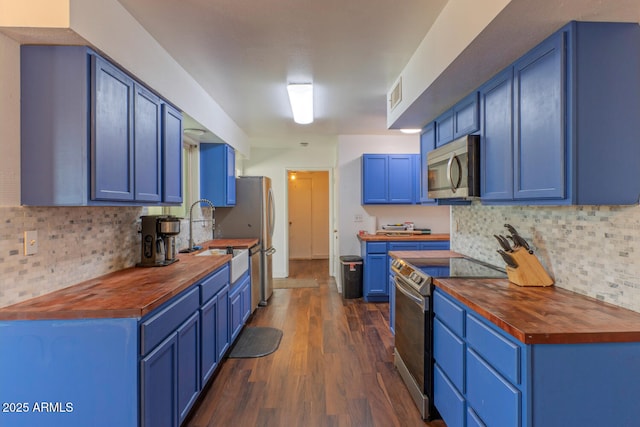 kitchen featuring blue cabinetry, appliances with stainless steel finishes, wooden counters, and a sink