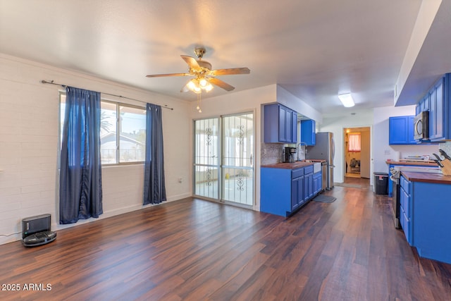 kitchen with blue cabinetry, dark wood-style flooring, appliances with stainless steel finishes, and butcher block counters