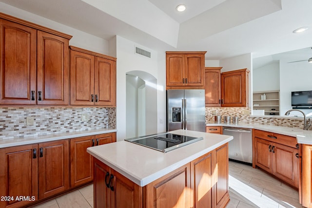 kitchen featuring a center island, decorative backsplash, sink, light tile patterned floors, and appliances with stainless steel finishes