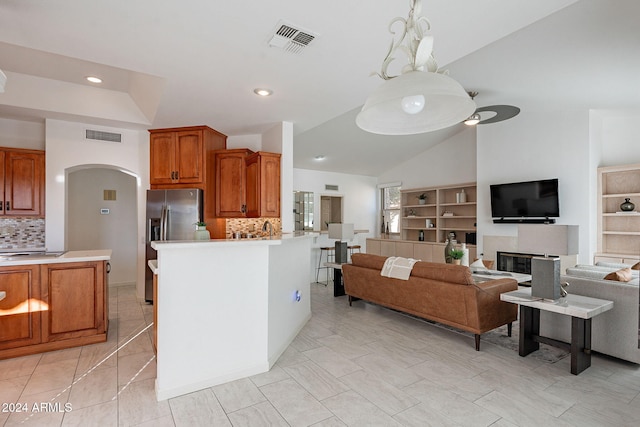 kitchen featuring built in features, lofted ceiling, backsplash, and stainless steel fridge