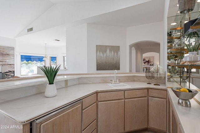 kitchen featuring kitchen peninsula, light brown cabinetry, sink, a chandelier, and lofted ceiling