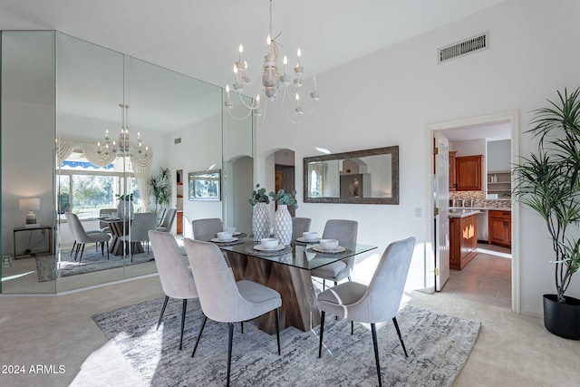 dining space featuring a towering ceiling, light colored carpet, and a chandelier