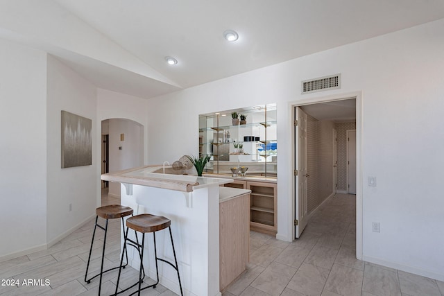 kitchen with a kitchen island with sink, a breakfast bar, and lofted ceiling