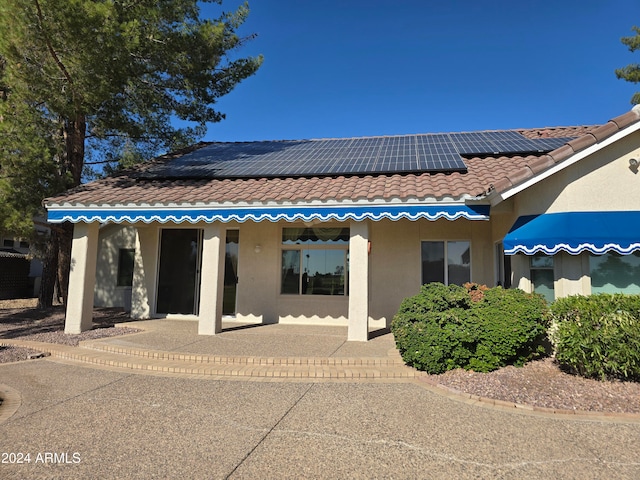 rear view of house with solar panels and a patio area