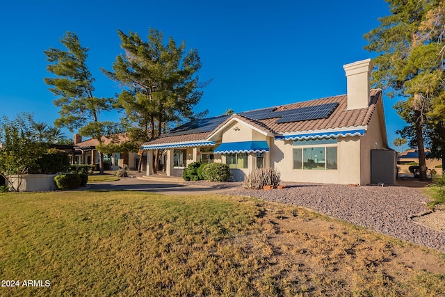 rear view of property featuring a lawn and solar panels