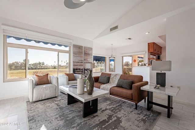 living room with a wealth of natural light, lofted ceiling, and a notable chandelier