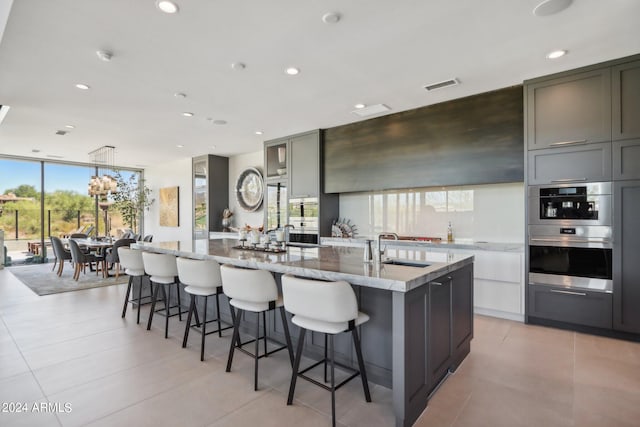 kitchen featuring gray cabinets, a wealth of natural light, a large island with sink, and sink