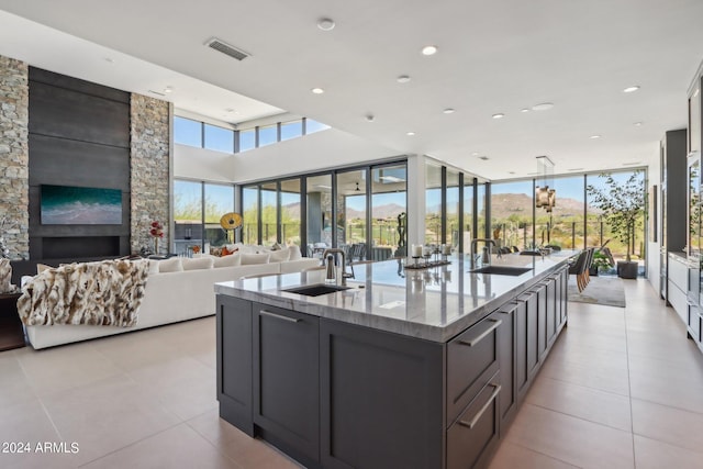 kitchen with an island with sink, light stone countertops, a fireplace, and sink