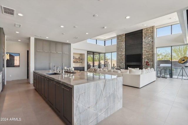 kitchen featuring a high ceiling, light stone countertops, a large island, and sink