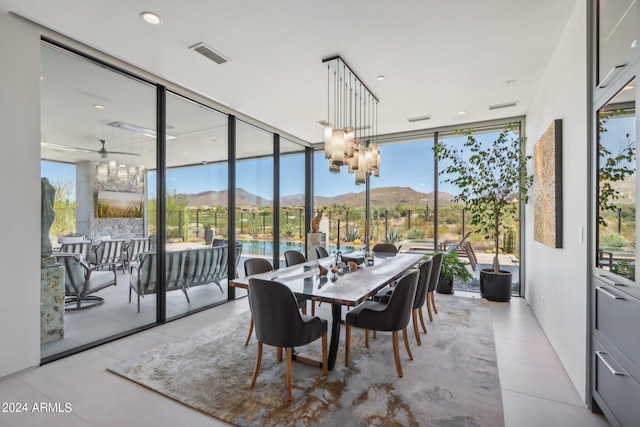 sunroom with a healthy amount of sunlight, ceiling fan with notable chandelier, and a mountain view