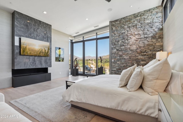 bedroom featuring access to outside, light wood-type flooring, and floor to ceiling windows