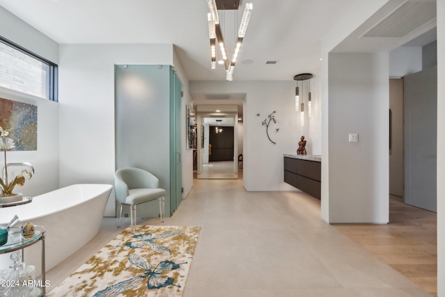 bathroom with a bath, vanity, hardwood / wood-style floors, and a notable chandelier