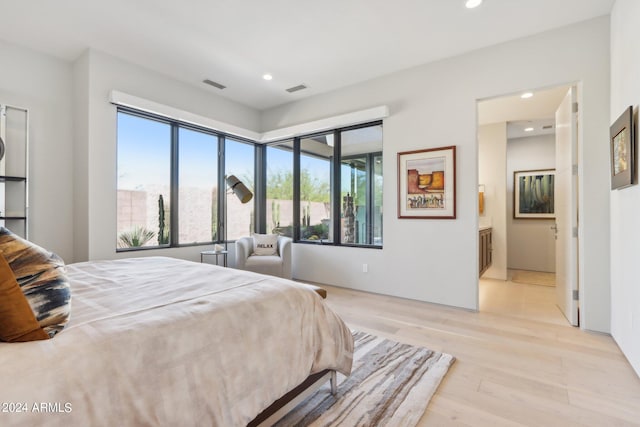 bedroom featuring light wood-type flooring and ensuite bath