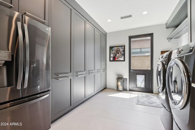 laundry room with cabinets, light tile patterned flooring, and washer and clothes dryer