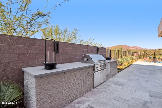 view of patio / terrace with a mountain view, an outdoor kitchen, and area for grilling