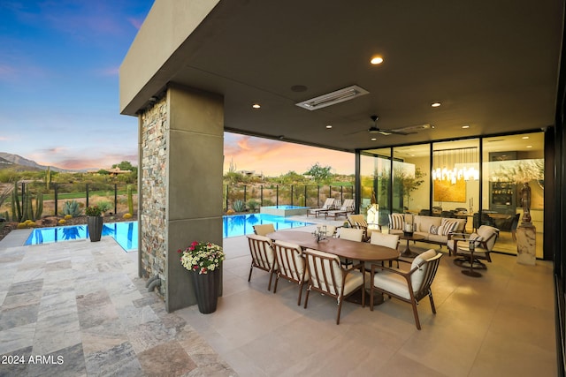 patio terrace at dusk featuring a fenced in pool