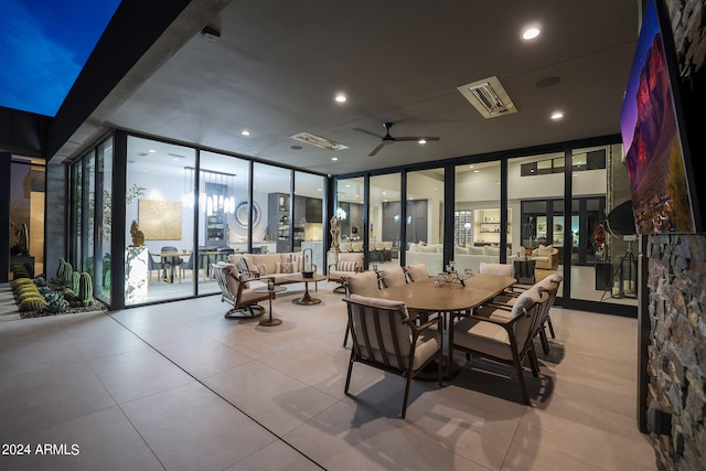 tiled dining space featuring ceiling fan and a wall of windows