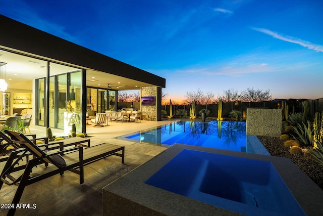 pool at dusk featuring ceiling fan and a patio area