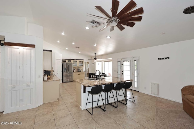 kitchen with a ceiling fan, a kitchen bar, stainless steel refrigerator with ice dispenser, light tile patterned floors, and lofted ceiling