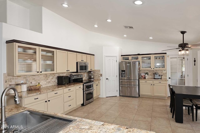 kitchen with visible vents, lofted ceiling, tasteful backsplash, a sink, and stainless steel appliances