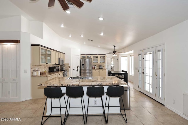 kitchen featuring ceiling fan, a breakfast bar area, appliances with stainless steel finishes, tasteful backsplash, and vaulted ceiling