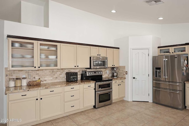 kitchen with cream cabinets, light tile patterned flooring, appliances with stainless steel finishes, backsplash, and visible vents