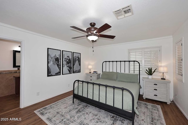 bedroom with crown molding, baseboards, visible vents, and wood finished floors