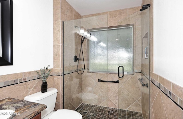 bathroom with vanity, toilet, tile walls, a wainscoted wall, and a stall shower