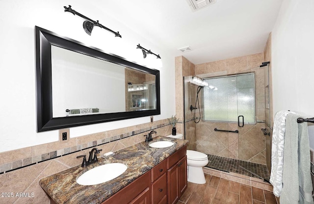 full bathroom with tile walls, visible vents, a shower stall, and a sink