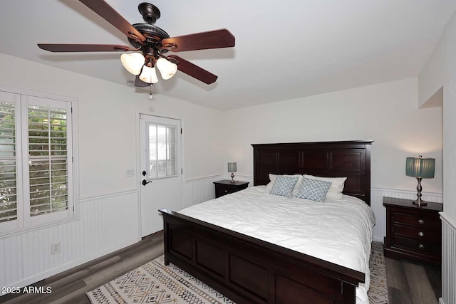 bedroom with ceiling fan, wainscoting, and wood finished floors