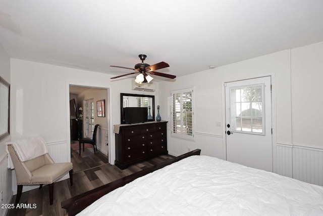 bedroom with a wainscoted wall, ceiling fan, a wall unit AC, and dark wood-type flooring