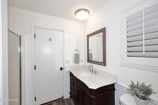 bathroom featuring vanity, wainscoting, wood finished floors, and toilet