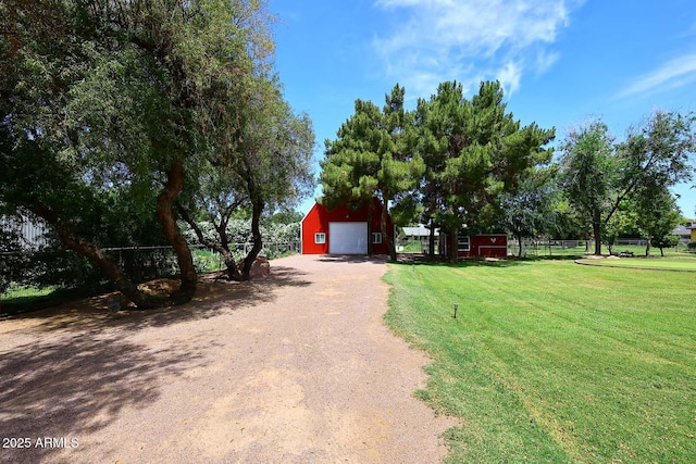 exterior space featuring an outdoor structure, a garage, dirt driveway, and fence