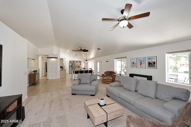 living room featuring ceiling fan, lofted ceiling, light carpet, and light tile patterned floors