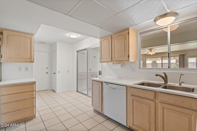 kitchen with sink, dishwasher, a drop ceiling, light tile patterned flooring, and light brown cabinetry