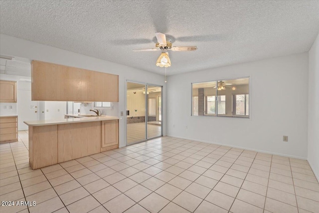 kitchen with light tile patterned flooring, light brown cabinetry, a textured ceiling, kitchen peninsula, and ceiling fan