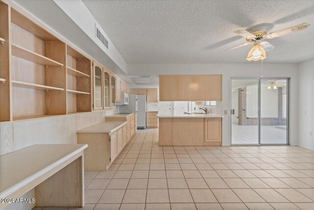 kitchen with a textured ceiling, light brown cabinetry, light tile patterned floors, ceiling fan, and kitchen peninsula