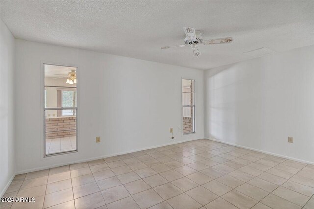 spare room with ceiling fan, light tile patterned flooring, and a textured ceiling