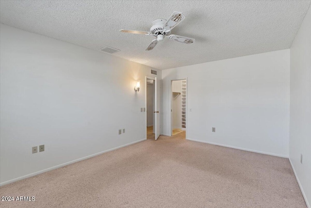 carpeted spare room with a textured ceiling and ceiling fan