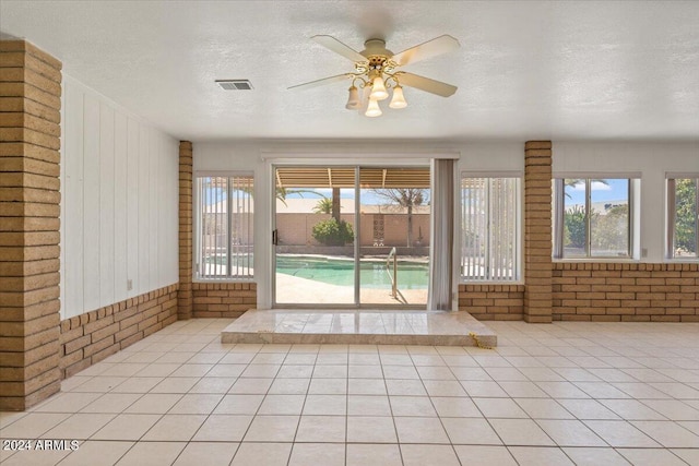 interior space featuring light tile patterned flooring, brick wall, and a textured ceiling