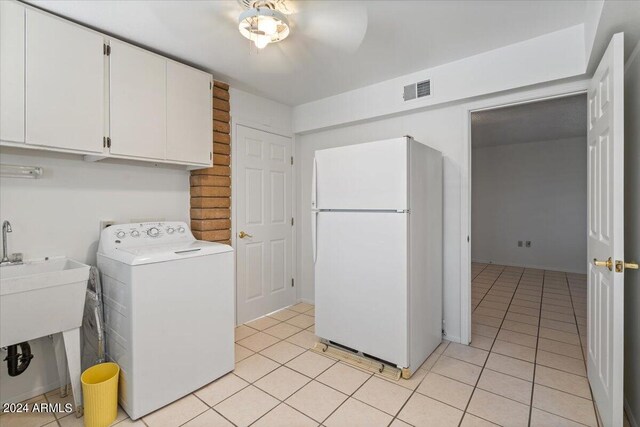 clothes washing area with cabinets, water heater, independent washer and dryer, light tile patterned floors, and sink