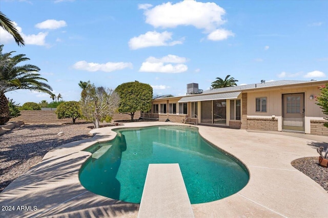 view of pool with a sunroom, a diving board, and a patio