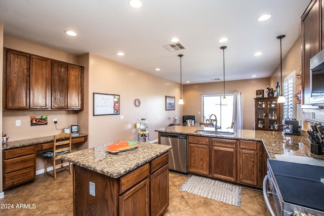 kitchen with an island with sink, pendant lighting, built in desk, and stainless steel dishwasher