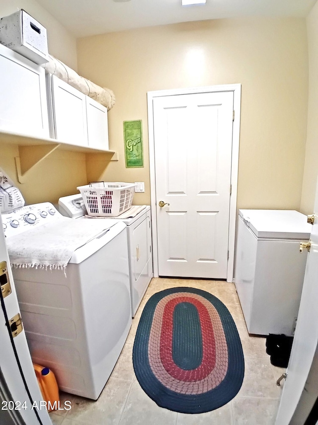 laundry area featuring cabinets, independent washer and dryer, water heater, and light tile patterned flooring