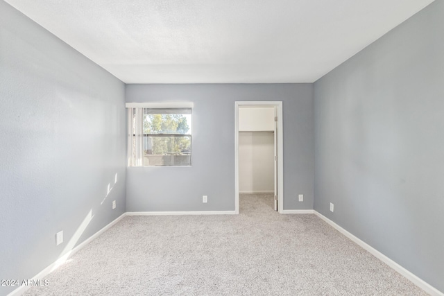 unfurnished bedroom with a spacious closet, light carpet, and a closet